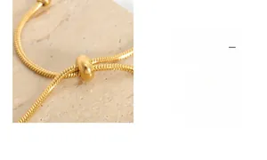 Detail of adjustable gold snake chain bracelet with sliding bead closure on stone surface