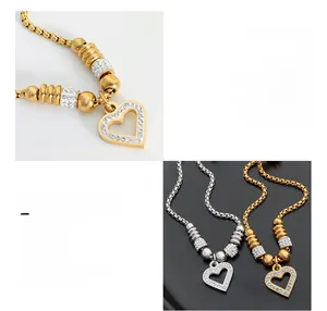 Close-up of heart-shaped charm with rhinestones and bead chain in gold and silver