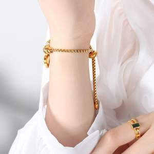 Gold box chain heart bracelet with emerald cut green stone ring set on female model