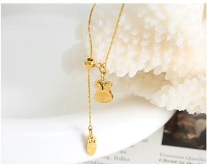 Detail of 18K gold plated bunny and carrot charms on a titanium steel chain necklace
