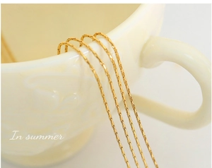 Detail of multi-layer 18K gold-plated chain showing intricate textures and bright metallic luster