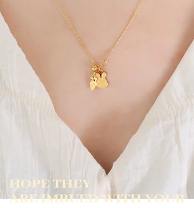 Detail of cute golden rabbit and carrot pendant necklace with tassel on a model