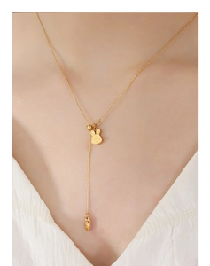 Detail of bunny pendant and carrot tassel on golden necklace worn by model