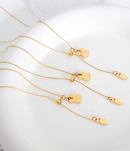 Detail of adjustable gold bunny necklace with carrot charm on white ceramic plate