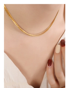 Detail of layered 18K gold-plated snake chains on model neck for elegant jewelry look