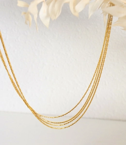 Detail view of elegant layered 18K gold plated chain necklaces on white background
