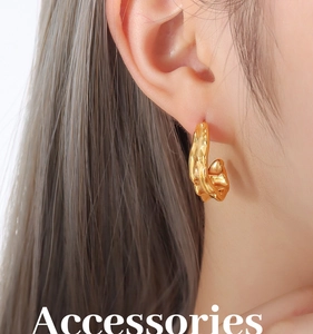 Close-up of golden irregular lava texture C-shaped earring worn on a female ear