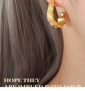 Close-up of 18K gold plated C-shaped earrings with irregular lava texture on model