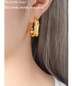 Close-up of golden irregular lava texture C-shape earrings worn by a model