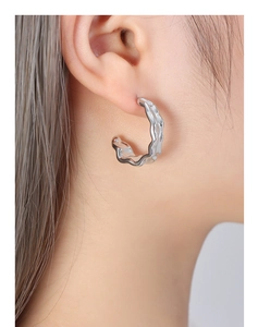 Detail view of silver C-shaped earrings with unique molten lava textured finish