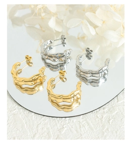 Macro detail of 18K gold and silver plated C-shaped earrings with unique lava texture