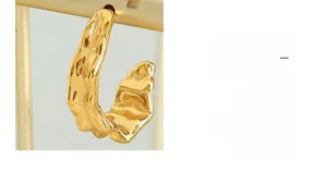 Macro view of gold-plated C-shaped earrings with unique irregular lava texture finish