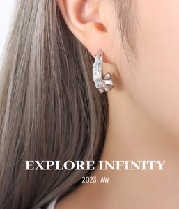 Close-up of silver C-shaped earrings with irregular lava texture on a model's ear