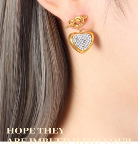 Detail of gold heart earrings with knot design and micro-set sparkling white rhinestones