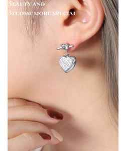 Macro shot of silver heart earrings with knot detail and sparkling pavé crystals