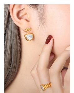 Detail of gold knot heart drop earrings with pave zircons and matching textured ring