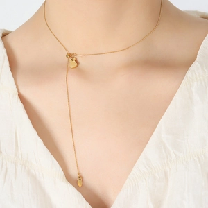 Cute bunny and carrot pendant necklace in gold finish worn by a model on white background