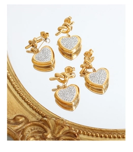 Macro detail of gold knot earrings with crystal-encrusted heart pendants on mirror