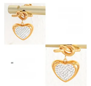 Detail of titanium steel heart earrings with white zircon stones in gold finish