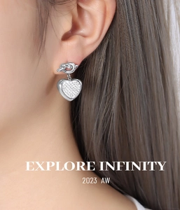Close-up of twisted silver earring featuring a heart-shaped pendant with pavé set crystals
