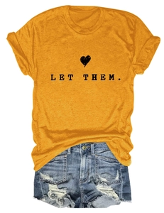 Detail of yellow Let Them T-shirt with heart graphic paired with ripped denim shorts