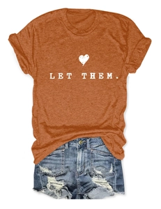 Detail view of burnt orange T-shirt with 'LET THEM.' print and frayed denim shorts