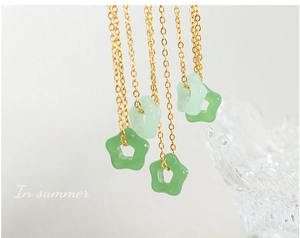 Détail macro de cinq pendentifs étoiles en jade Hetian sur fines chaînes dorées
