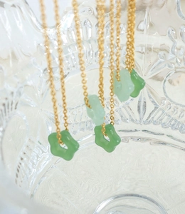 Vue macro de colliers dorés avec pendentifs fleurs évidées vertes sur verrerie