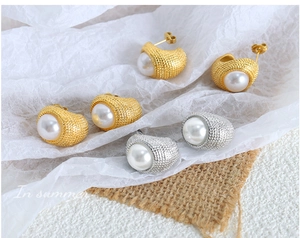 Macro detail of French vintage C-shaped gold and silver earrings with faux pearls