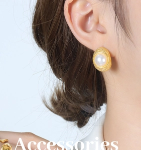 Close-up of vintage C-shape gold plated pearl earrings worn on a female ear