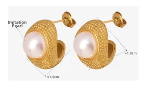 Detailed macro view of C-shaped gold-plated earrings with imitation pearl and texture