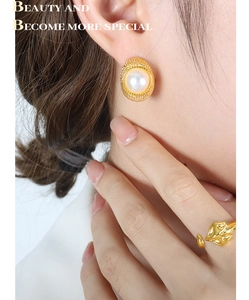 Close-up of pearl C-shaped earrings and fox-shaped open ring in vintage gold finish