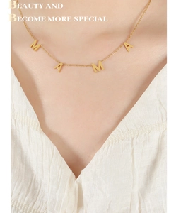 Gros plan d'un collier doré avec pendentif MAMA porté par un mannequin en col V
