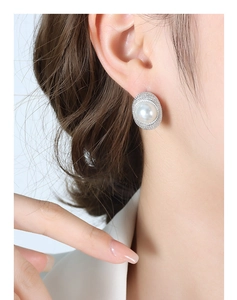 Macro view of vintage French pearl stud earring with elegant silver-plated C-shape frame