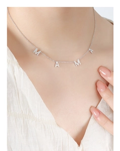 Gros plan du collier avec pendentif MAMA argenté porté au cou pour la fête des mères