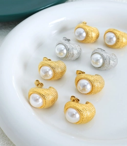 Close-up of vintage C-shaped gold and silver earrings with textured grid and pearls