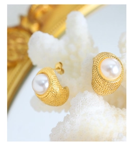 Macro detail of gold C-shaped earrings with textured finish and white pearl inlay