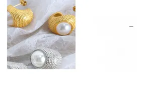 Macro detail of vintage textured gold and silver C-shaped earrings with large faux pearls