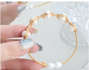 Detailed close-up of handmade gold wire-wrapped bracelet with white freshwater pearls