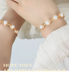 Detail showing handmade brass gold wire wrapped bracelets with round white pearls
