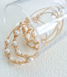 Macro detail of handmade brass wire wrapping on white baroque freshwater pearl bracelet