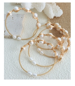Macro view of handmade brass bracelets with baroque freshwater pearls on rustic burlap
