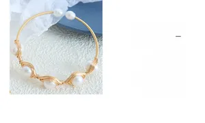 Detail of handcrafted gold wire bracelet featuring baroque freshwater pearls and open design