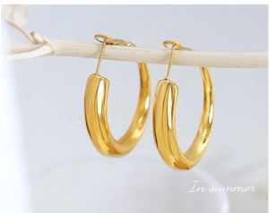 Nahaufnahme dicker goldener Creolen mit Hochglanzfinish auf einem weißen Ast