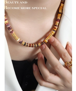 Detail of colorful stone beaded necklace with gold accents worn with a white blazer