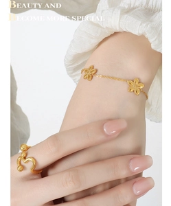 Detail eines eleganten Goldgänseblümchen Armbands und Wellenrings an einem Model