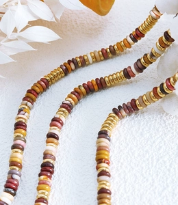 Detailed macro view of colorful natural stone heishi beads with gold plated accents