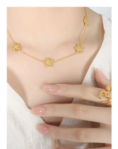 Detailansicht der goldenen Blumenkette und des Wellenrings an einem Model in Weiß