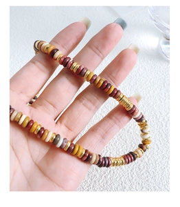 Detailed macro view of colorful flat stone beads and gold metal spacers on jewelry