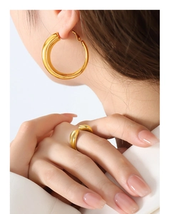 Nahaufnahme eines Models mit klobigen goldenen Creolen und einem minimalistischen Ring
